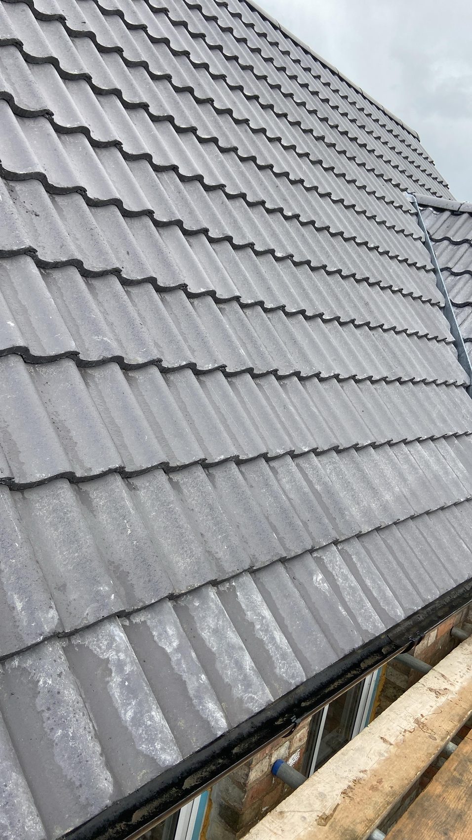 New grey interlocking tiles laid across a re-covered slope down to the new eaves