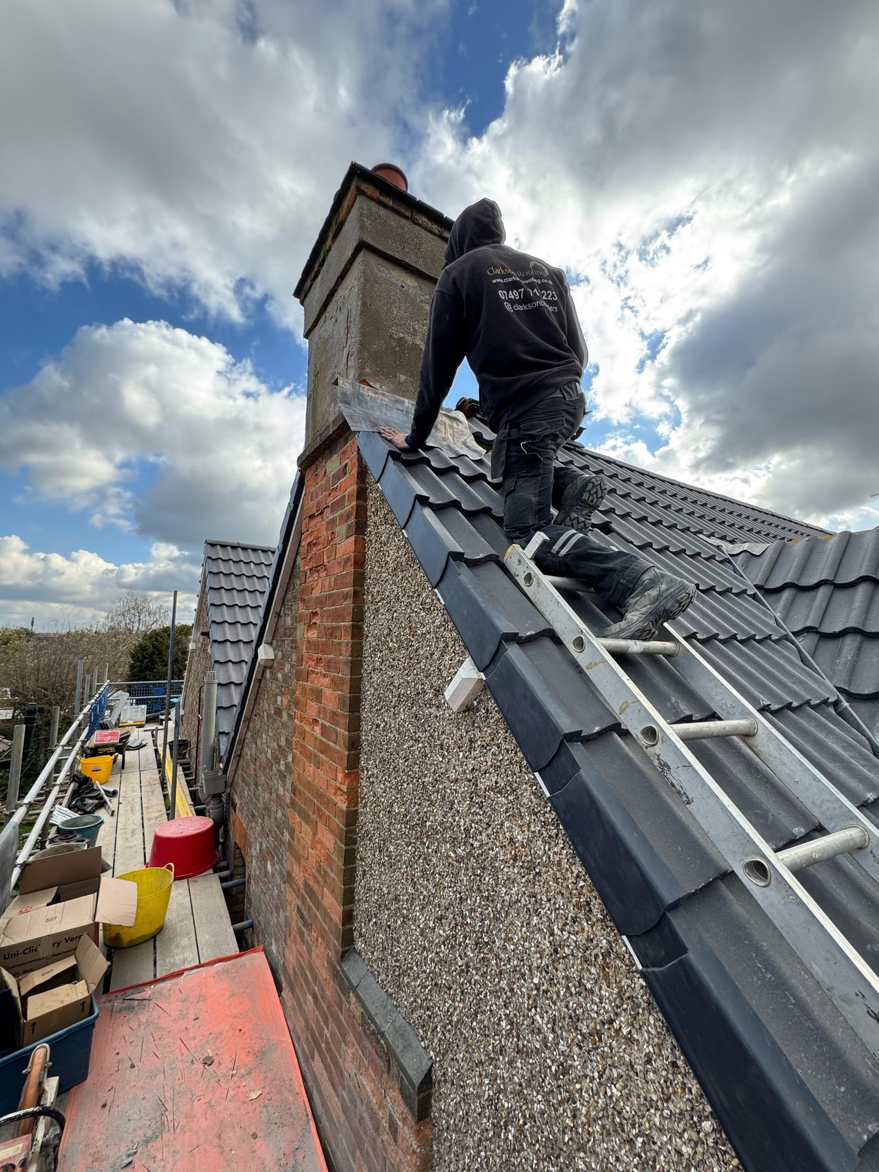 Clarkson Roofing roofer setting new grey tiles beside the chimney on the Bedford roof
