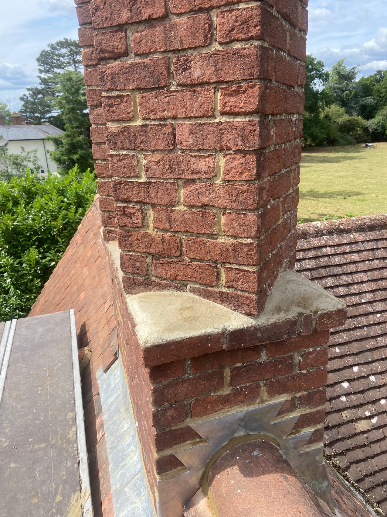 Freshly re-flaunched chimney shoulder with new sand and cement weathering against the sky