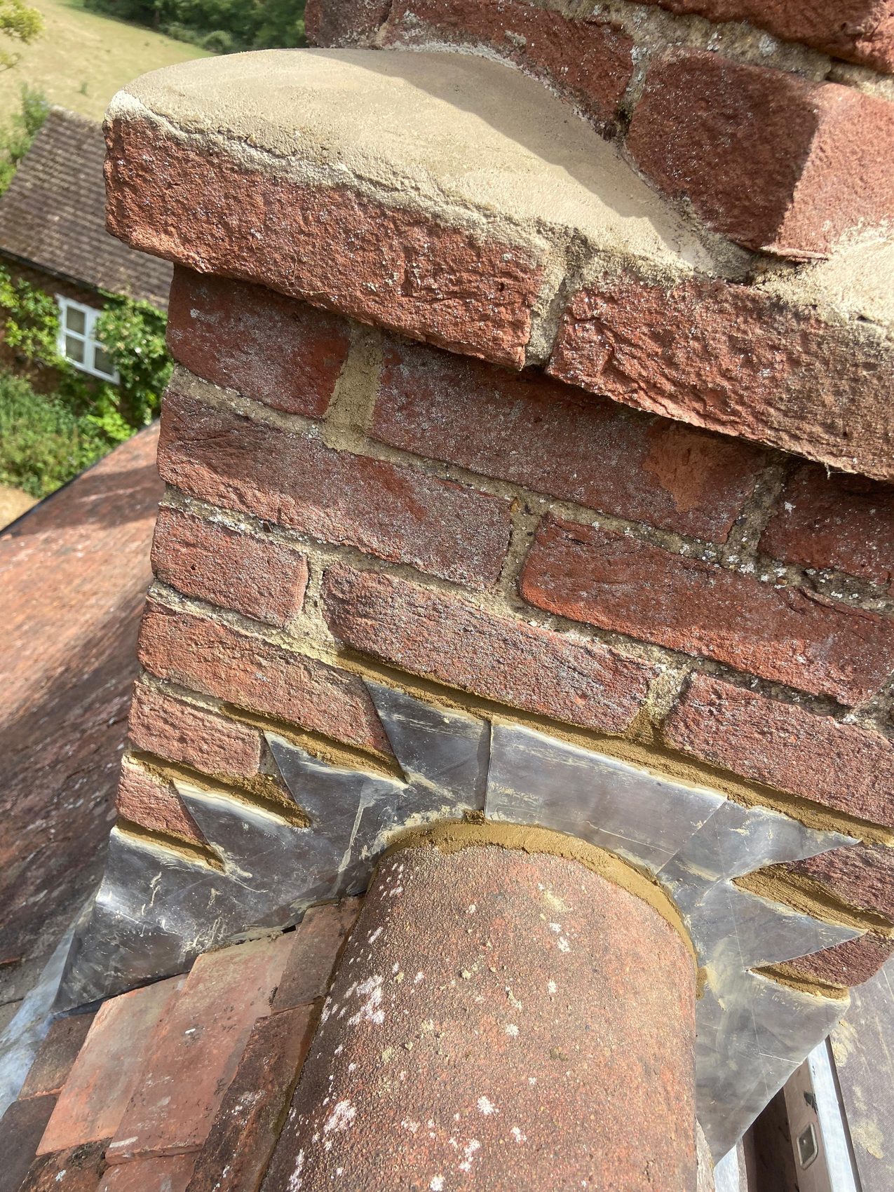 New lead flashing dressed around a repointed brick chimney