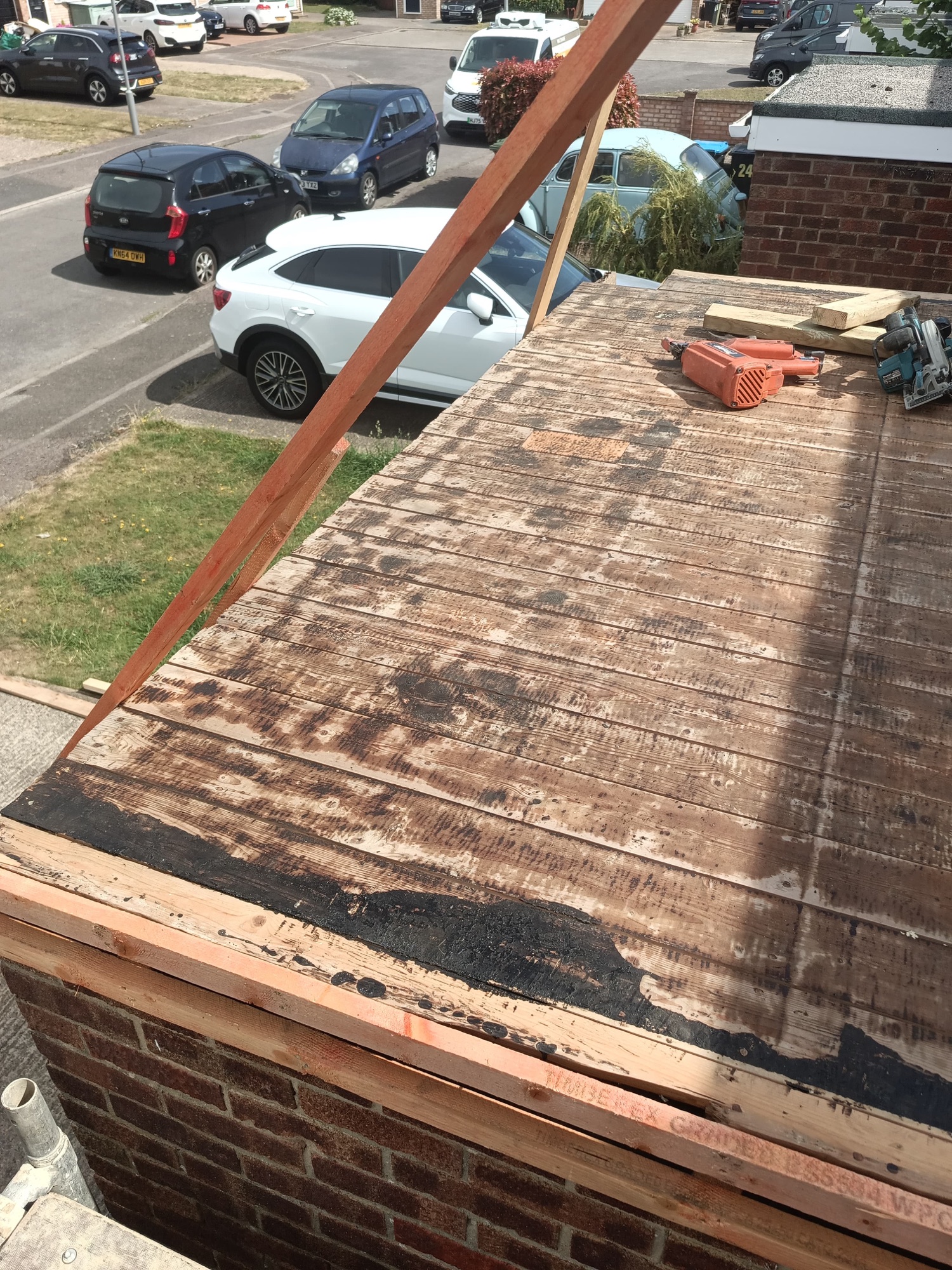 Failing garage flat roof stripped back to a rotten, water-stained timber deck