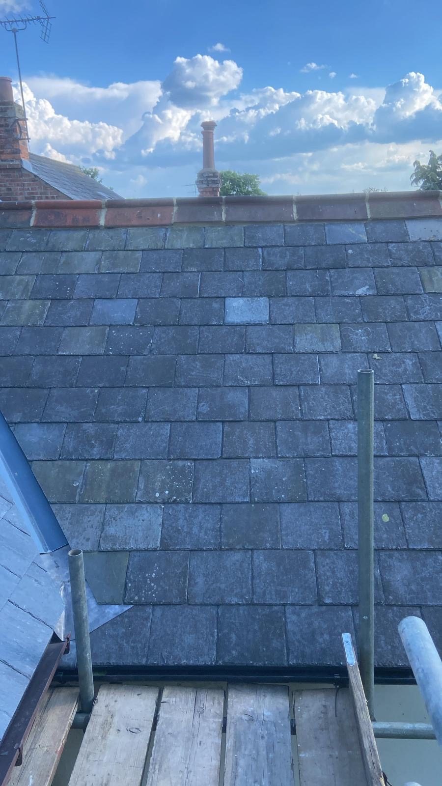 Reclaimed slate slope running up to a red clay ridge, with lead detail at the eaves