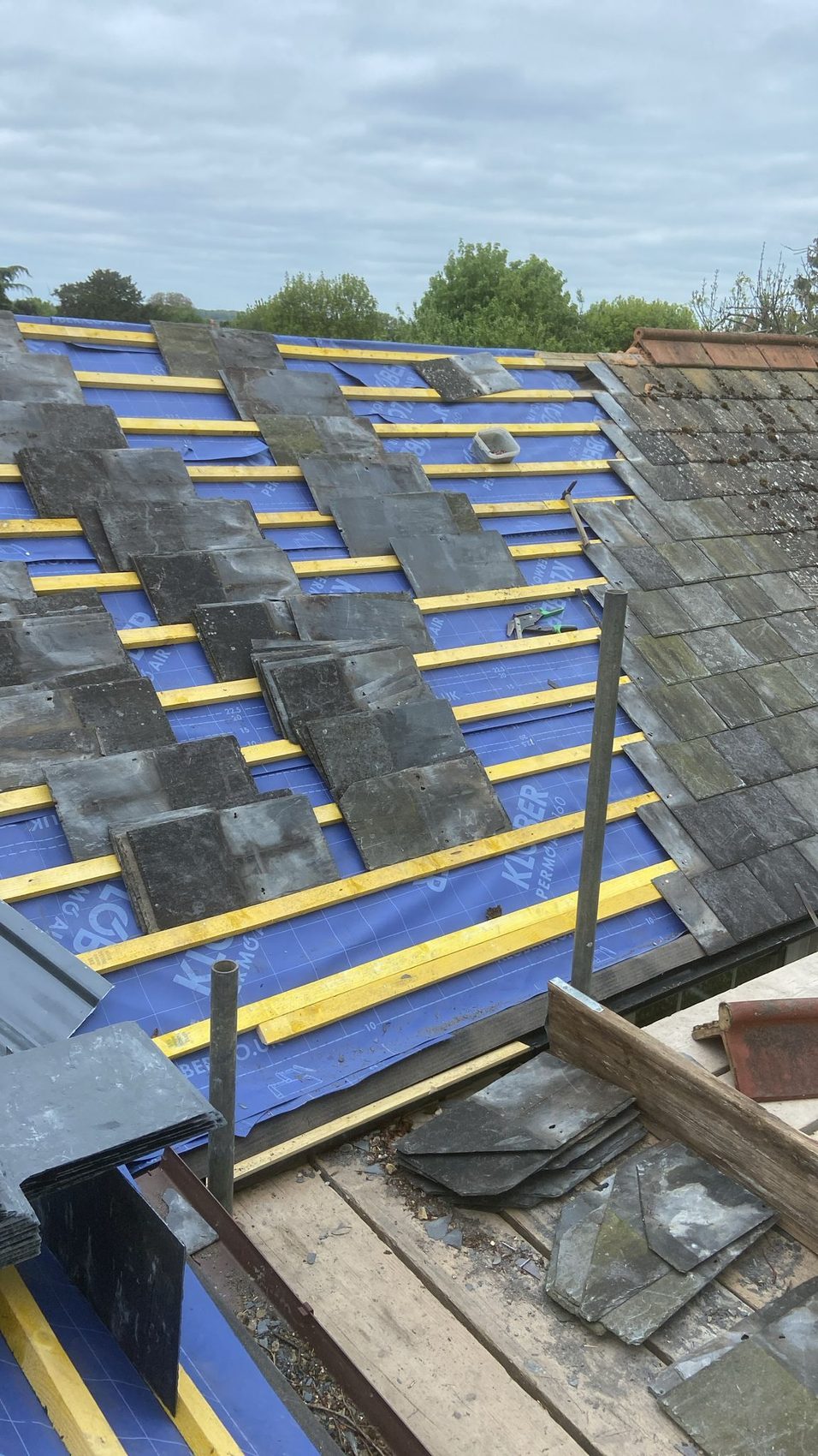 Reclaimed slate being laid course by course over the new battens