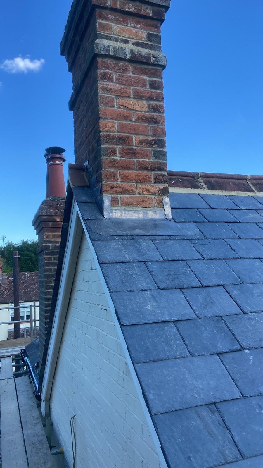 Reclaimed slate meeting a brick chimney with new lead flashing and soakers