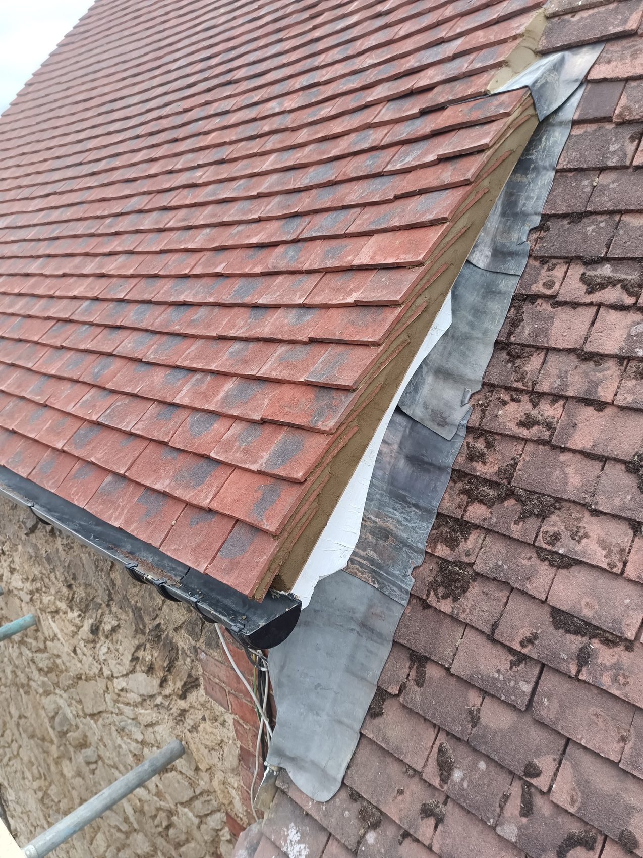 New plain clay tile meeting the retained roof with lead flashing