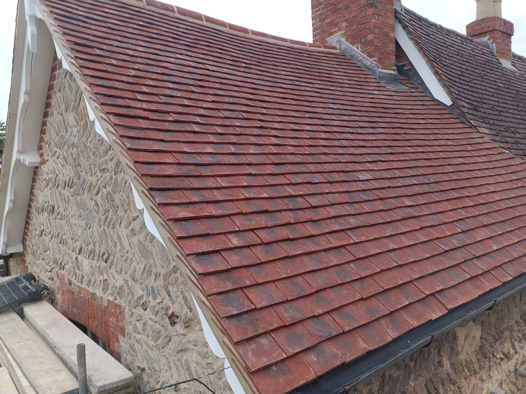 Finished Sherington period cottage roof re-tiled in red plain clay with a stone gable