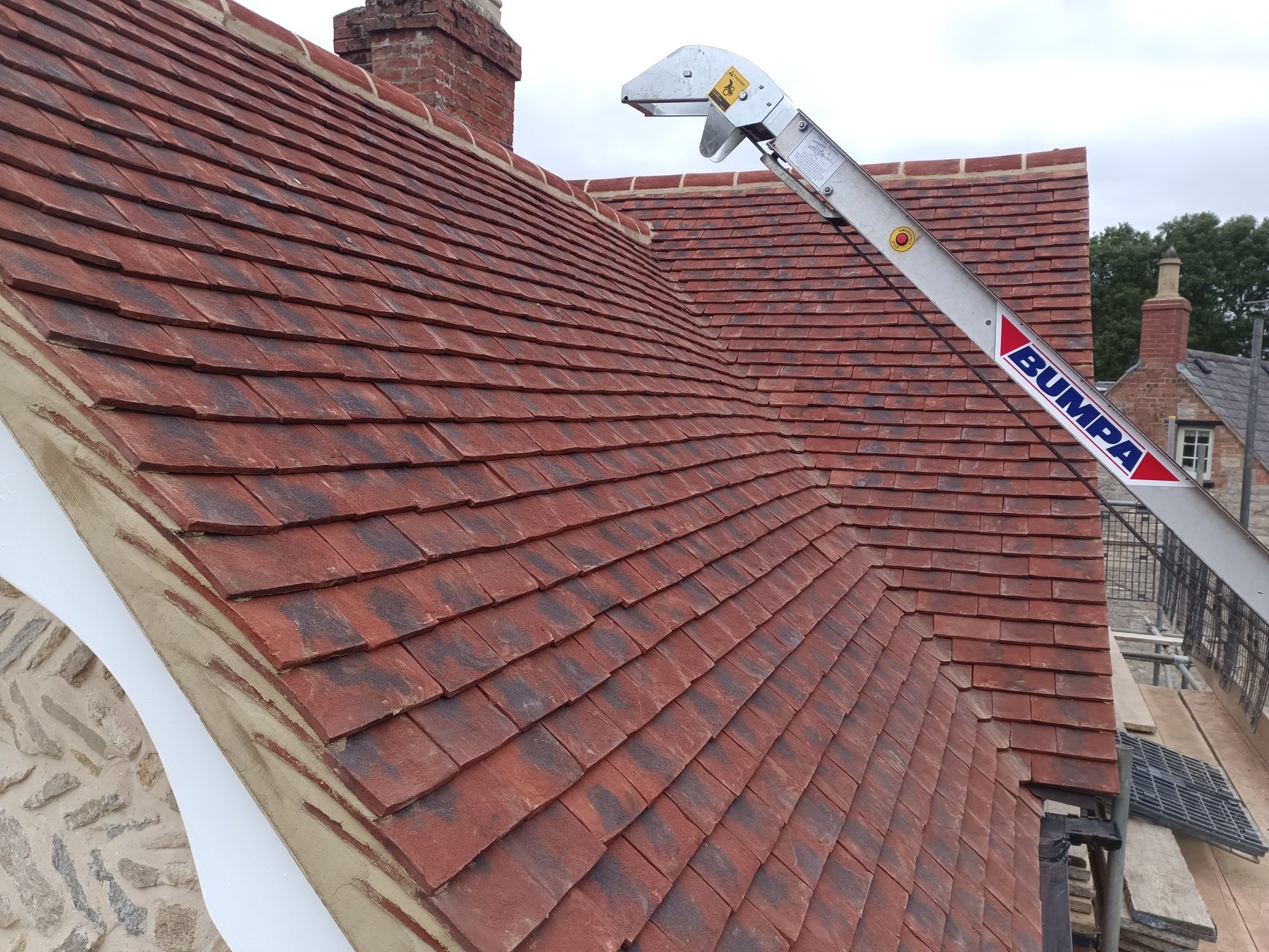 Plain clay tiles hoisted up and laid across the new roof